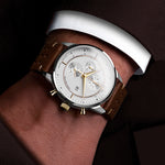 Luxury chronograph with brown leather strap on a wrist against a dark background