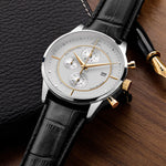 Luxury watch with black leather strap and silver case on a wooden surface