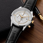 Luxury watch with black leather strap and silver case on a wooden surface