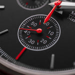 Close-up of a watch face with red hands and black dial