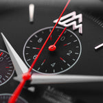 Close-up of a Matthew Mercury watch face with red and silver accents on a dark background
