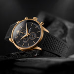 Magnum Gold chronograph with black dial and textured black rubber strap, featuring a gold case and pushers, against a dark background.