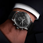 Close-up of a person wearing a black wristwatch with a dark face.