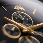 Macro shot of the Magnum Black chronograph by Matthew Mercury Watches. Dial with 18K gold hands, sub‑dials and hour markers on a black background.